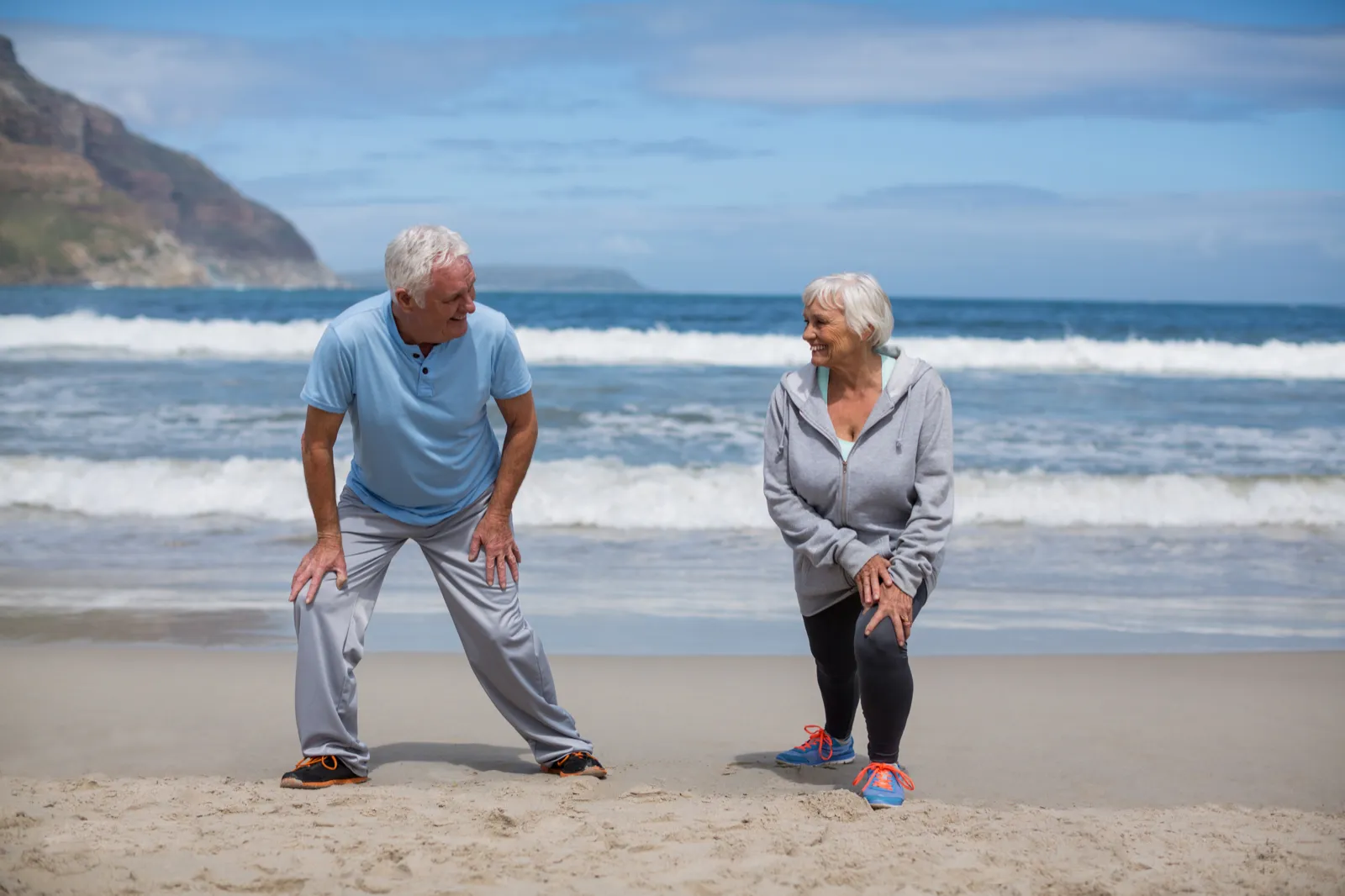 Pareja mayor haciendo ejercicio de estiramiento en la playa