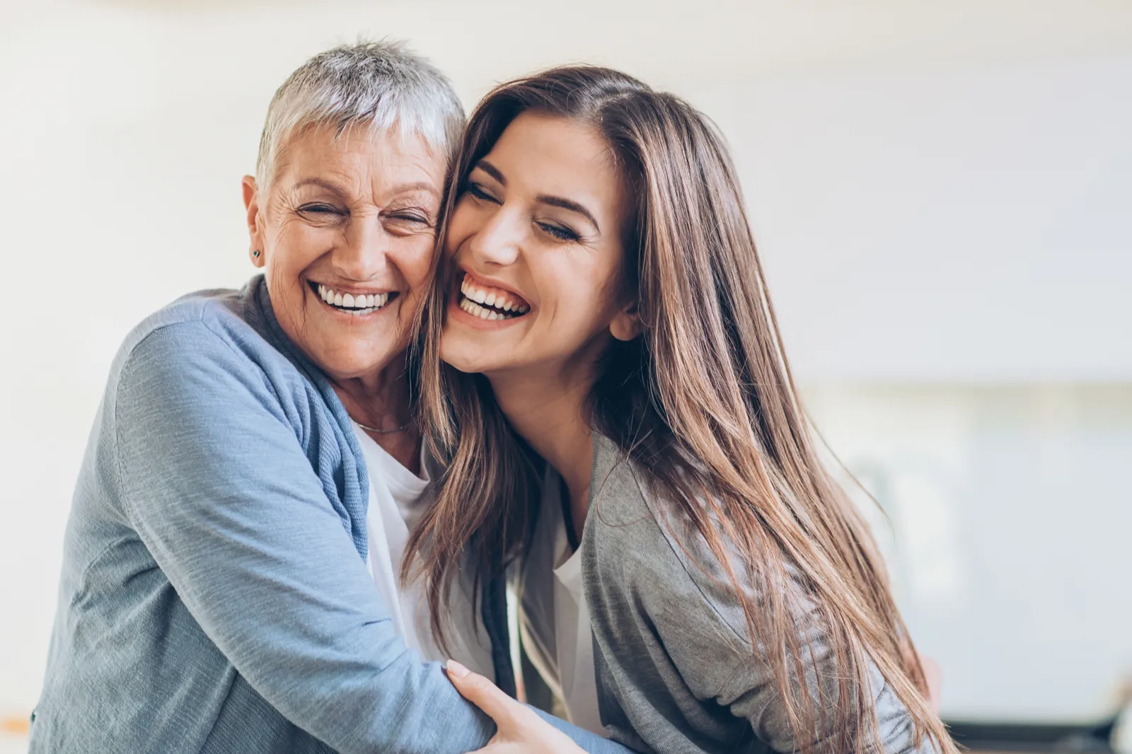 Mujer mayor y su hija abrazadas y sonriendo
